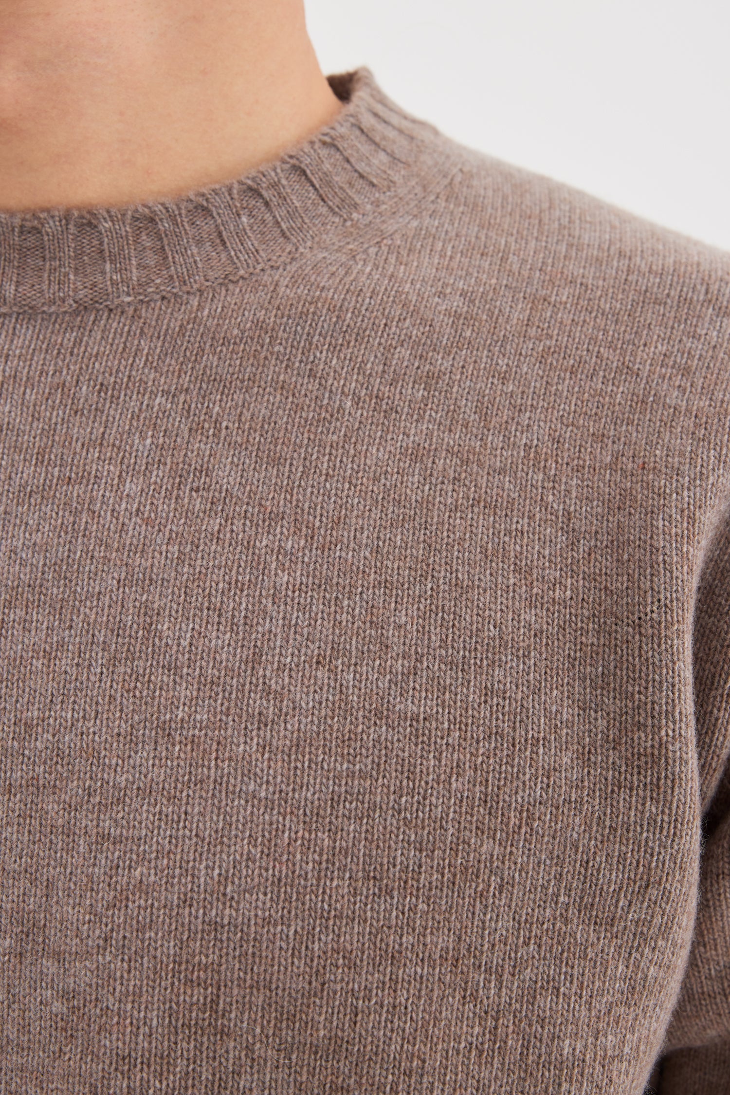 Close-up of a brown sweater with a plain background